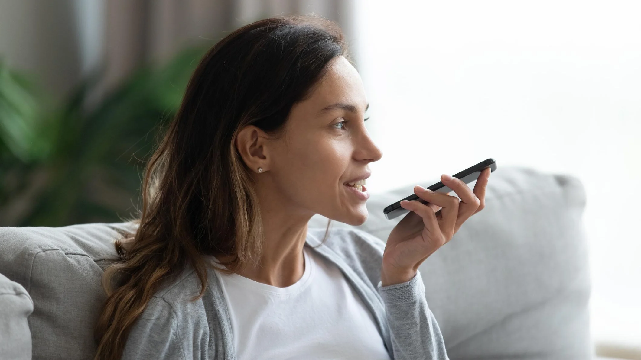 Women talking to her AI voice assistant on her phone @iStock